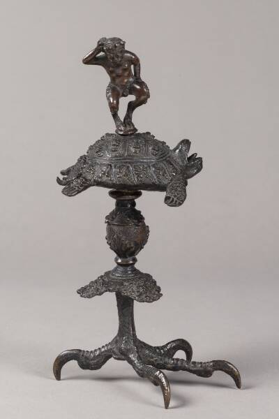 Olielampe (?). Pan-figur dansende på en skilpadde, der hviler på en baluster, som bæres af en rovfugleklo