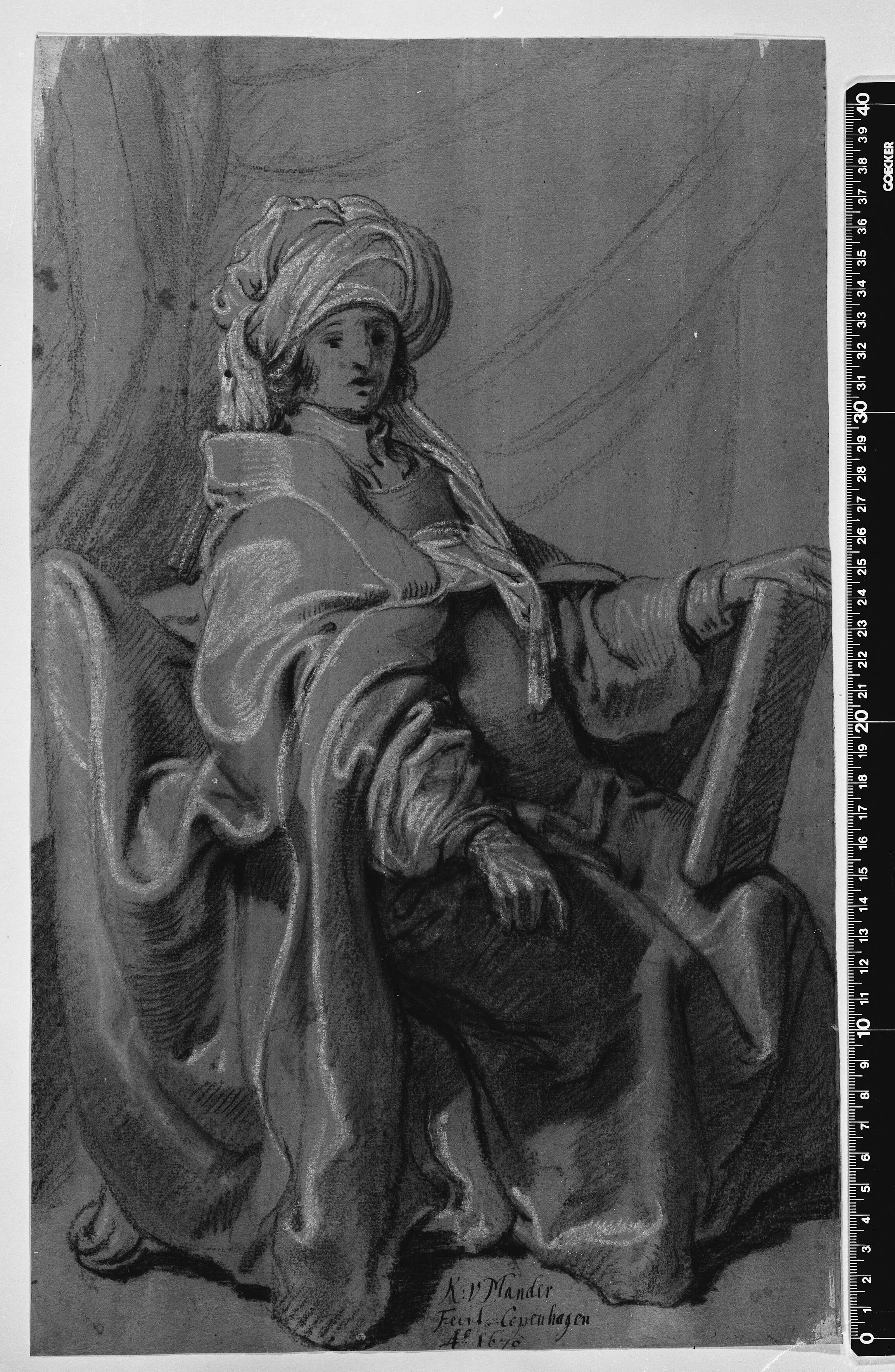 Siddende figur i kappe og turban, holdende en bog. Vendt mod højre.
