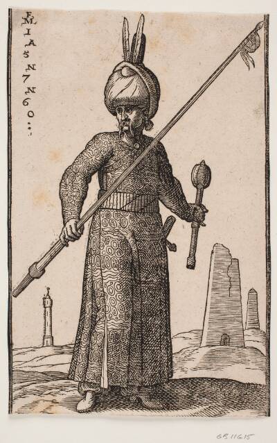 Stående soldat, skildret frontalt; i højre hånd en lanse med en vimpel på spidsen, i venstre en kølle og på hovedet en turban med to fjer; i baggrunden et "fyrtårn" samt to obelisk-lignende bygninger